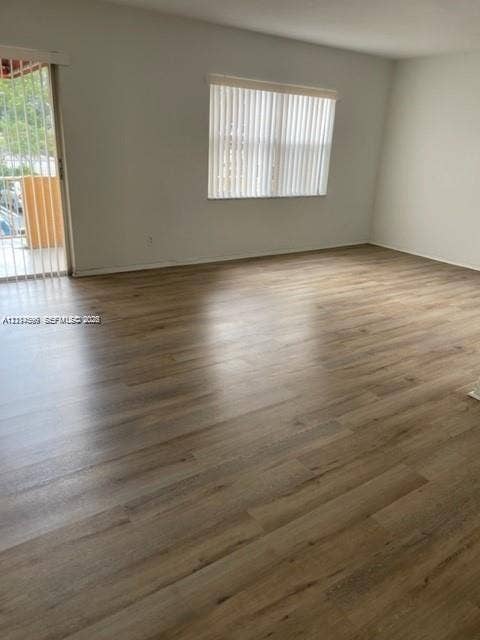 17901 NW 68th Avenue, #R202, Hialeah, Hialeah, FL 33015 Interior space featuring wood-finish flooring, neutral wall paint, a window with vertical blinds, and a sliding glass door