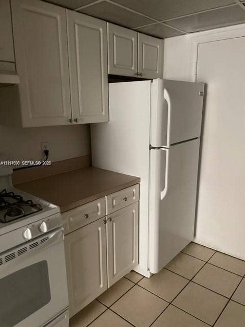 17901 NW 68th Avenue, #R202, Hialeah, Hialeah, FL 33015 Kitchen featuring white shaker-style cabinetry, solid-surface countertops, square tile flooring, and a white top-mount refrigerator