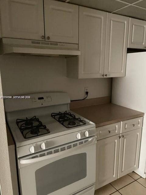 17901 NW 68th Avenue, #R202, Hialeah, Hialeah, FL 33015 Kitchen area featuring white cabinetry, a white gas range with integrated vent hood, and solid-surface countertops