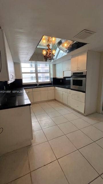 5255 Collins Avenue, #5J, Miami Beach, Miami Beach, FL 33140 Kitchen featuring light-toned cabinetry, contrasting dark countertops, built-in wall oven, tiled flooring, and a mirrored ceiling element with integrated lighting