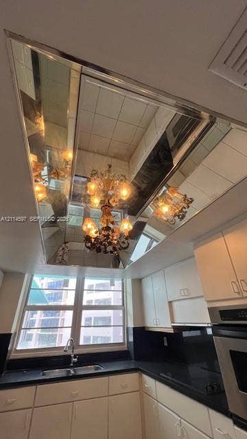 5255 Collins Avenue, #5J, Miami Beach, Miami Beach, FL 33140 Tray ceiling featuring a recessed mirrored panel, multi-tiered chandelier with decorative glass shades, solid surface countertops, and white cabinetry