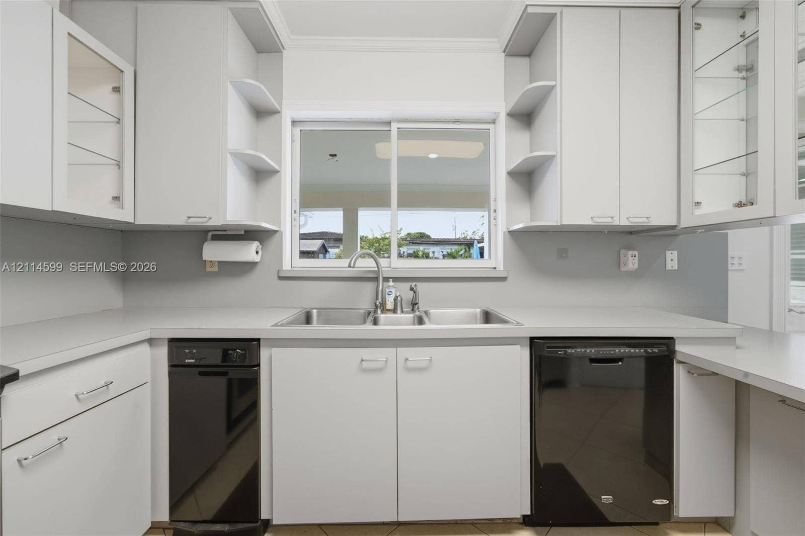 Kitchen featuring flat-panel cabinetry, open shelving, dual-basin stainless steel sink, solid-surface countertops, and contrasting black appliances