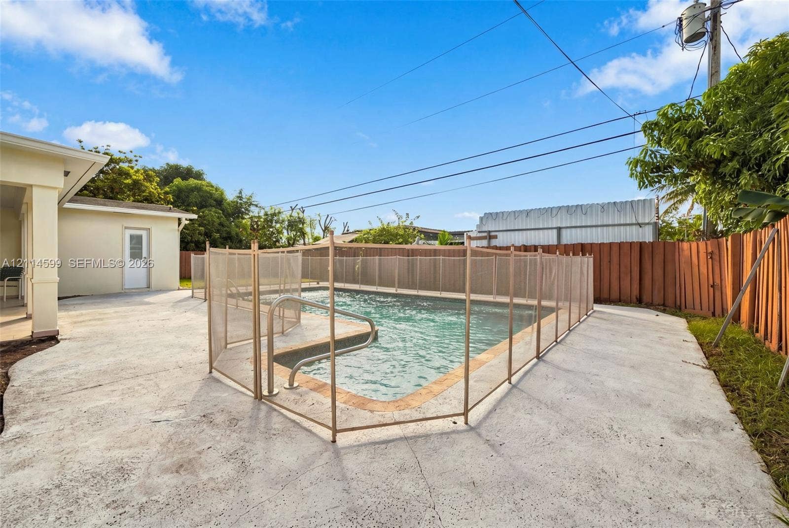 In-ground swimming pool featuring a perimeter safety fence, concrete decking, and surround fencing