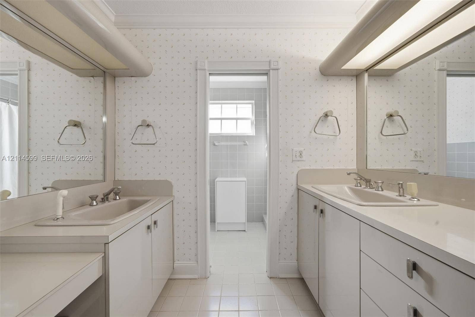 Dual-vanity bathroom featuring solid-surface countertops, integrated sinks, built-in cabinetry, and oversized wall-mounted mirrors with integrated lighting