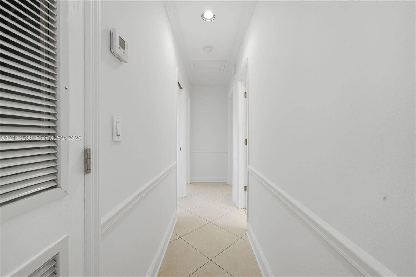 Hallway featuring neutral tile flooring, chair rail molding, and recessed ceiling lighting
