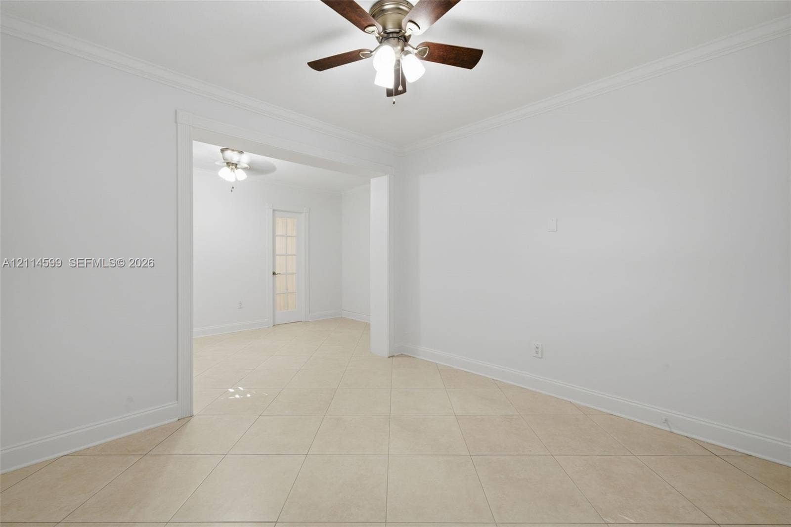 Interior space featuring large-format ceramic tile flooring, crown molding, a multi-light ceiling fan with dark wood-finish blades, and a glass-paneled interior door