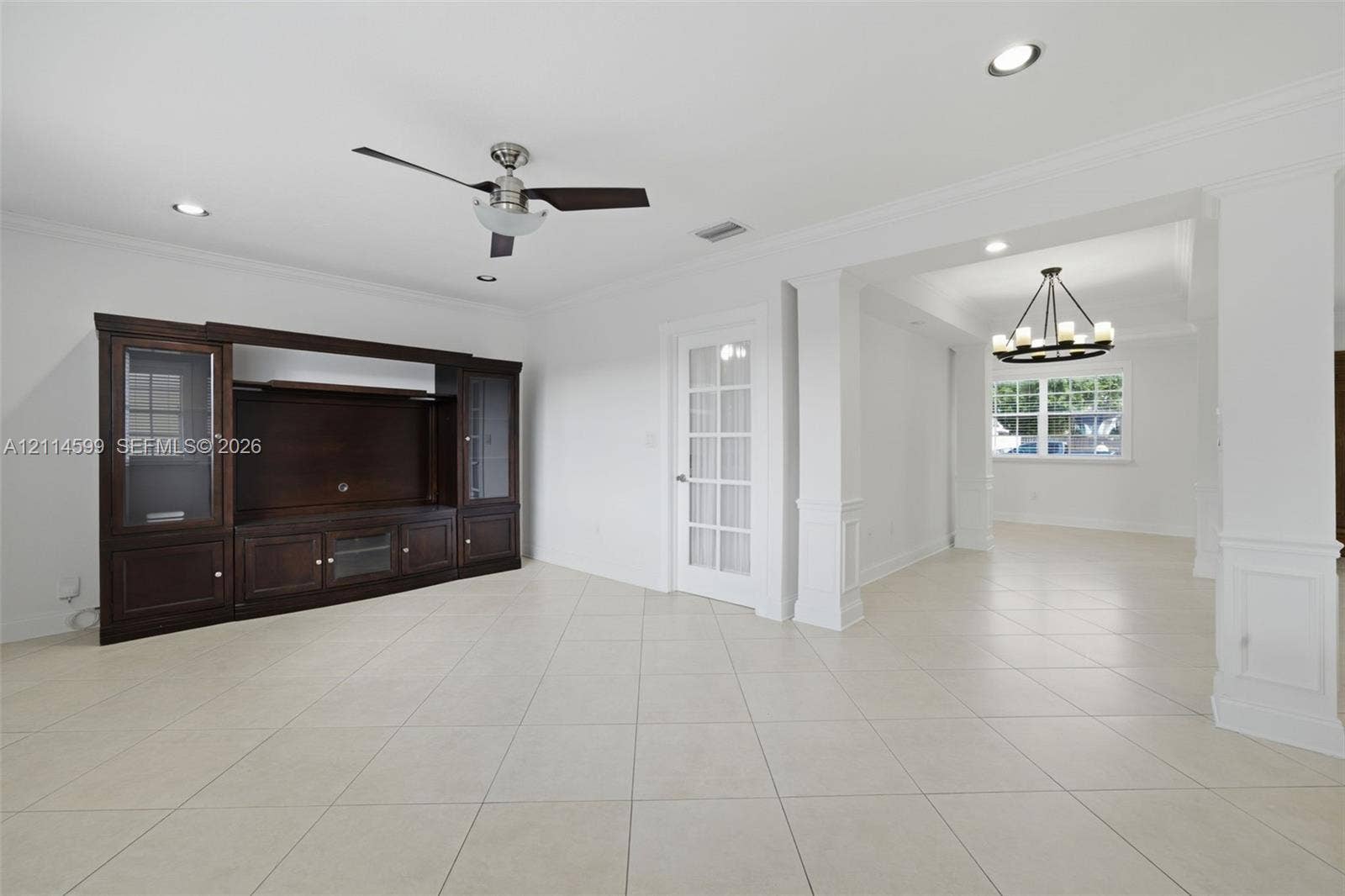 Built-in dark wood cabinetry with glass display panels, ceramic tile flooring, recessed lighting, crown molding, and a French door