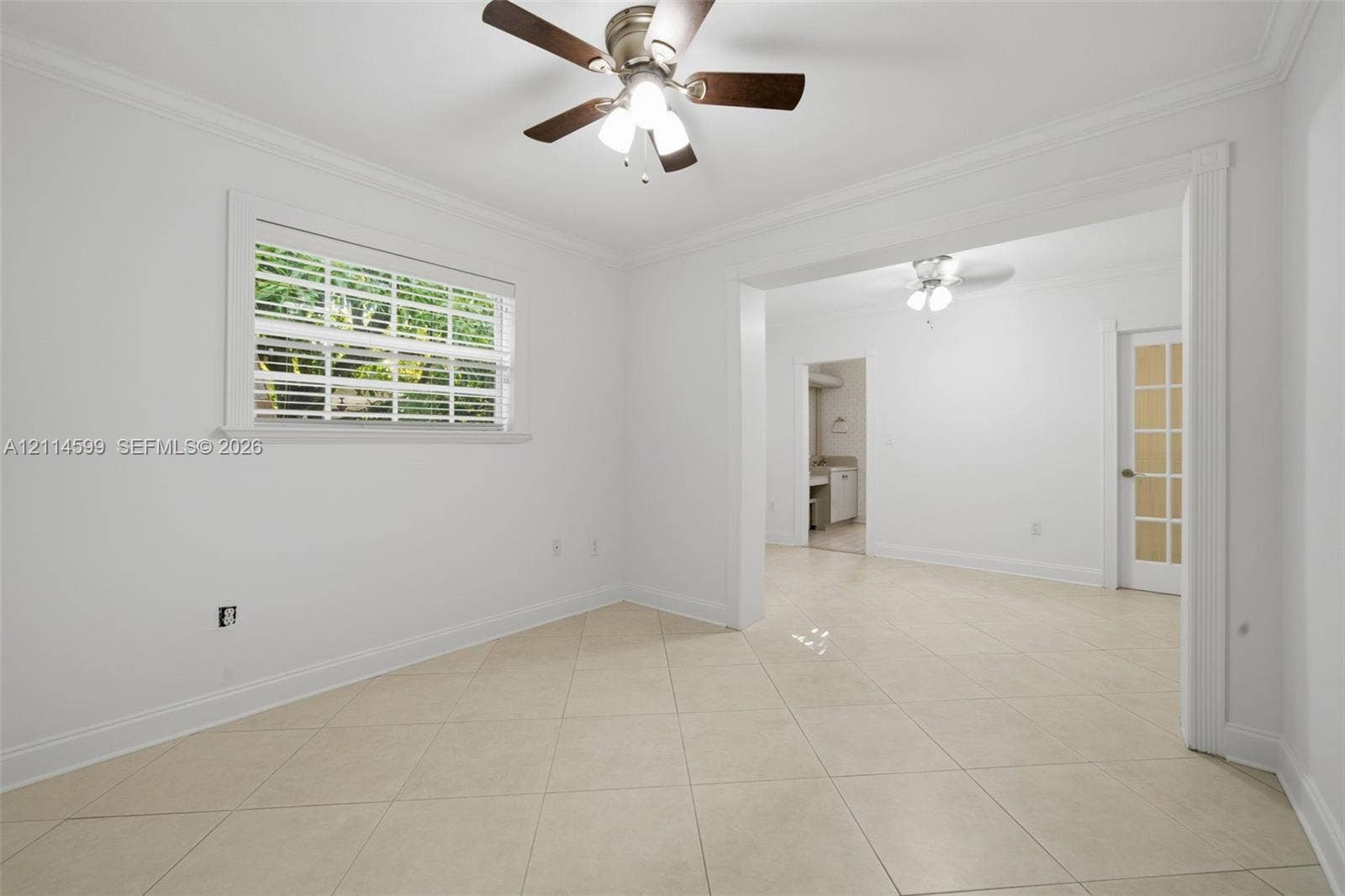 Interior space featuring large-format diagonal tile flooring, ceiling fans with integrated light kits, crown molding, and a glass-paneled door