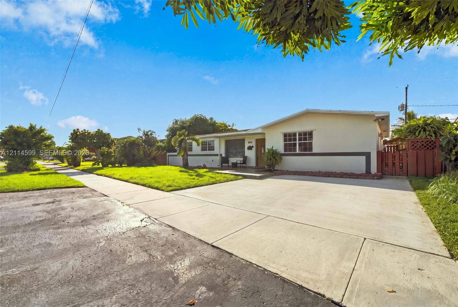 Single-story residence featuring a smooth stucco exterior, multi-pane windows, a concrete driveway, and gated side yard access