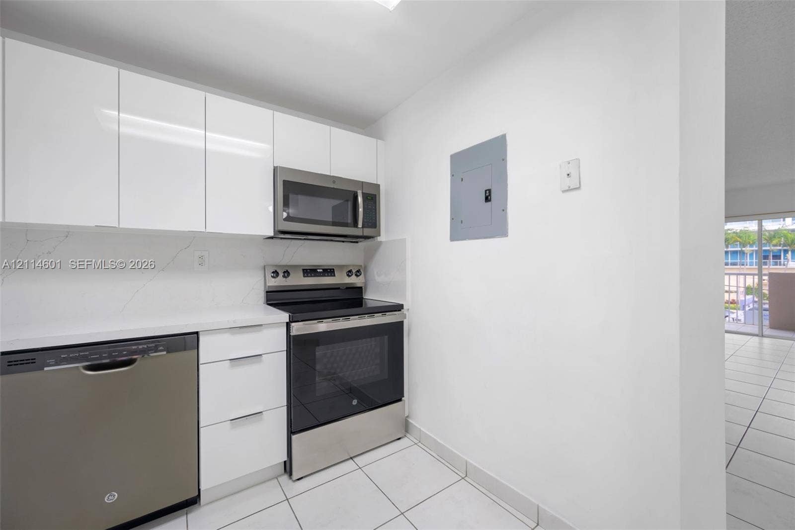 6801 Harding Avenue, #311, Miami Beach, Miami Beach, FL 33141 Kitchen featuring gloss-finish cabinetry, stone-surface countertops, tile backsplash, and stainless-steel appliances including a built-in microwave and range