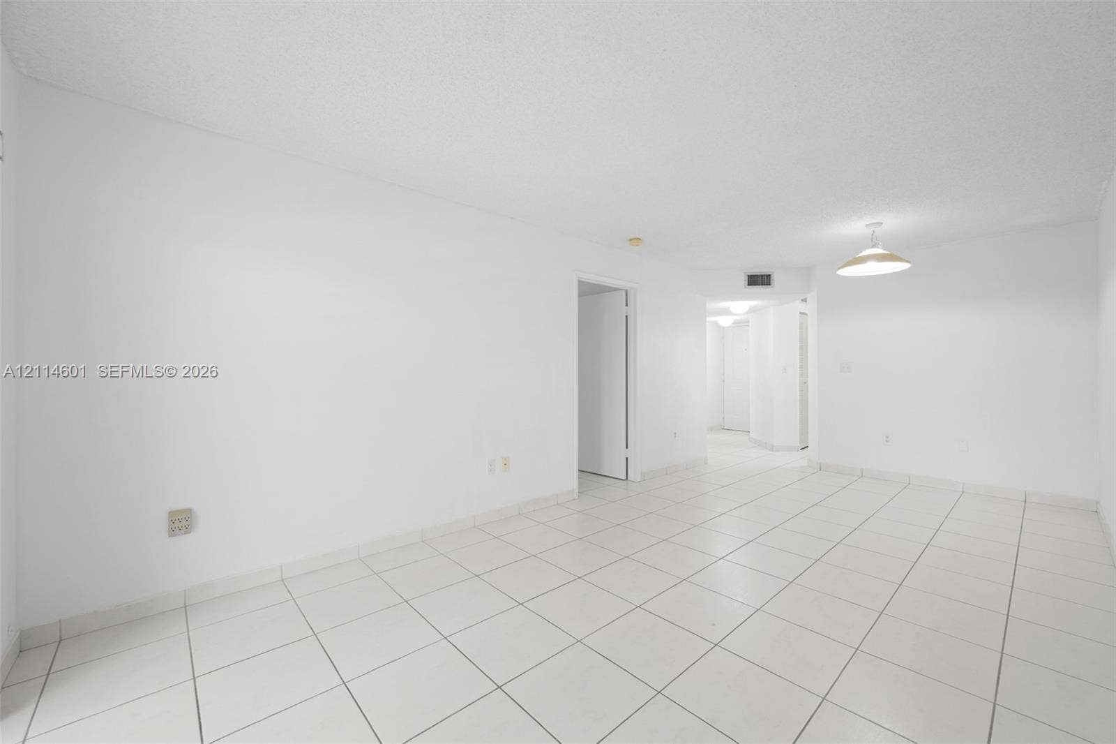 6801 Harding Avenue, #311, Miami Beach, Miami Beach, FL 33141 Open interior space featuring light-toned tile flooring, white walls, and a bowl-style pendant light fixture
