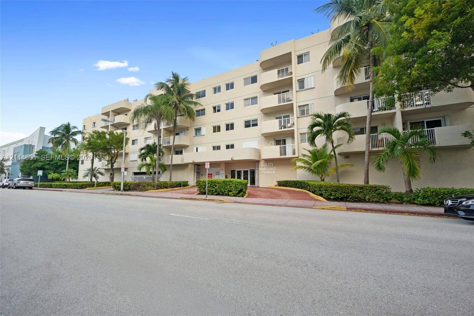 6801 Harding Avenue, #311, Miami Beach, Miami Beach, FL 33141 Multi-story residential building featuring private balconies, stucco exterior, and mature palm tree landscaping