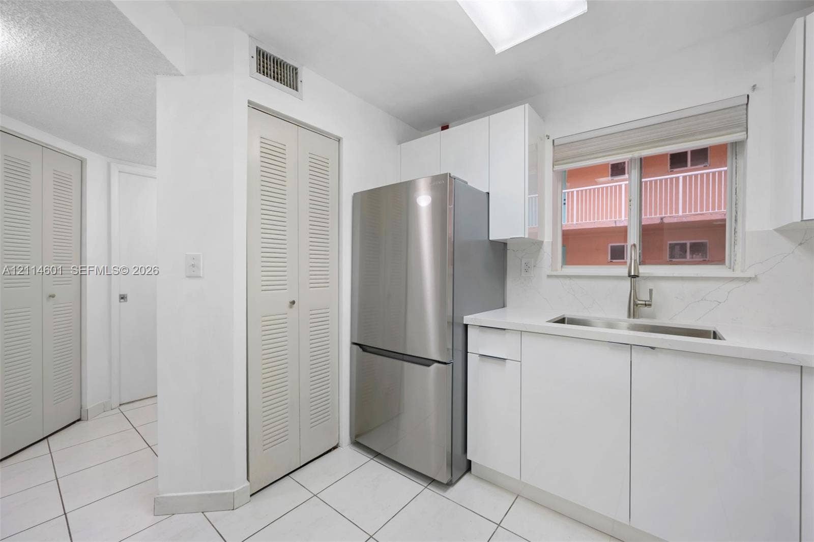 6801 Harding Avenue, #311, Miami Beach, Miami Beach, FL 33141 Kitchen featuring white cabinetry, stainless steel refrigerator, stone-composite countertop, undermount stainless steel sink with pull-down faucet, and white tile flooring
