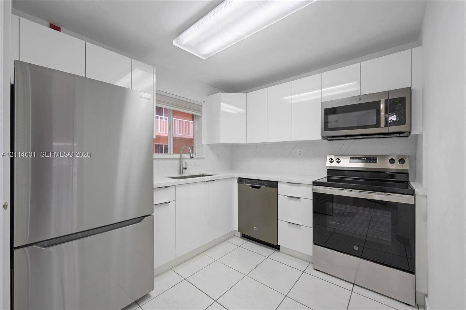 6801 Harding Avenue, #311, Miami Beach, Miami Beach, FL 33141 Kitchen featuring high-gloss white cabinetry, white stone-finish countertops, stainless steel appliance suite, and light-toned floor tile