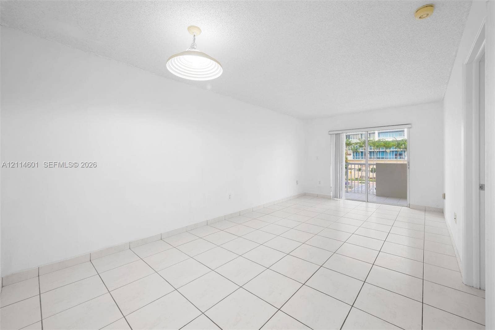 6801 Harding Avenue, #311, Miami Beach, Miami Beach, FL 33141 Neutral-toned interior featuring ceramic tile flooring, a dome-style pendant light fixture, and sliding glass doors leading to an exterior balcony
