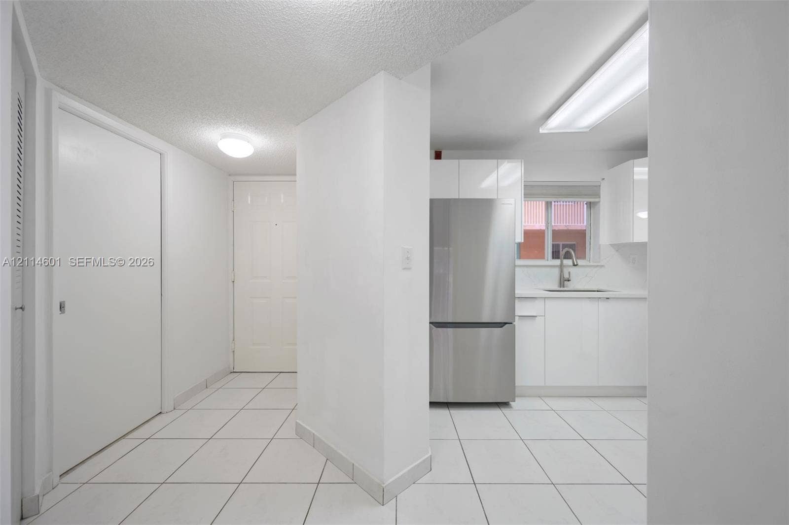 6801 Harding Avenue, #311, Miami Beach, Miami Beach, FL 33141 Kitchen featuring white cabinetry, stainless steel refrigerator, undermount sink, and white tile flooring