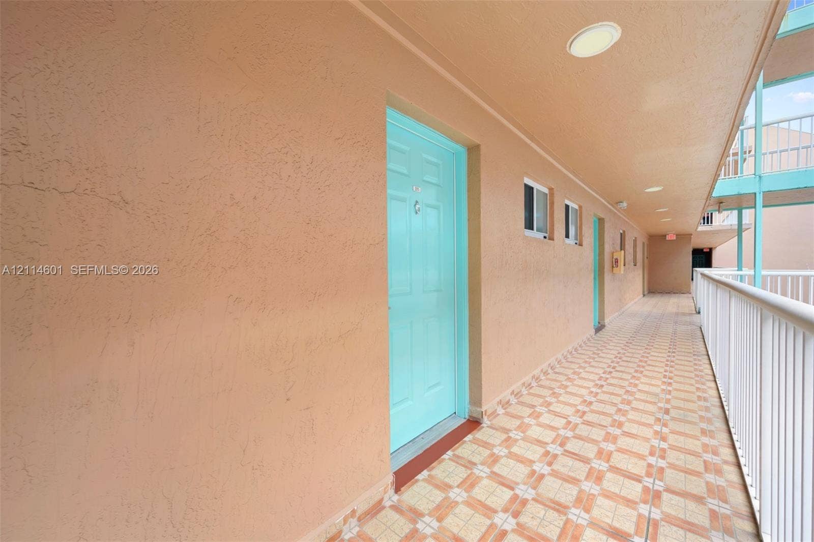 6801 Harding Avenue, #311, Miami Beach, Miami Beach, FL 33141 Exterior walkway featuring textured stucco walls, tiled flooring, recessed ceiling lighting, and white metal railing