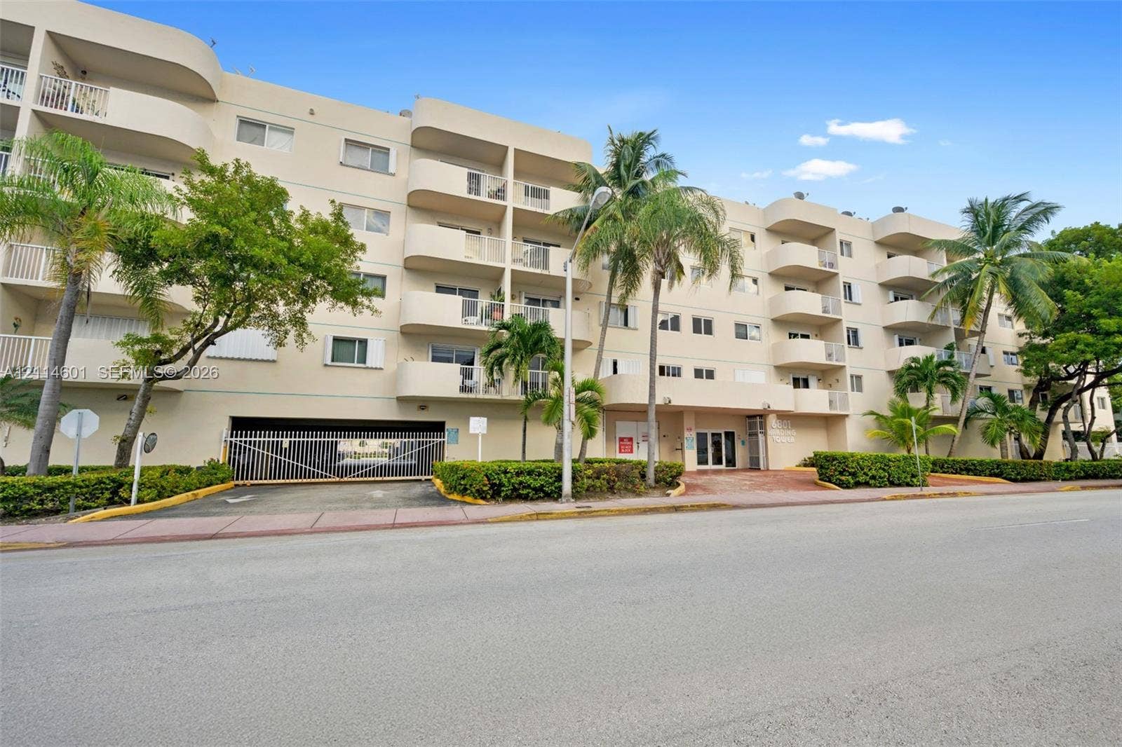 6801 Harding Avenue, #311, Miami Beach, Miami Beach, FL 33141 Multi-story building exterior featuring rounded balconies, secure gated parking access, and tropical landscaping