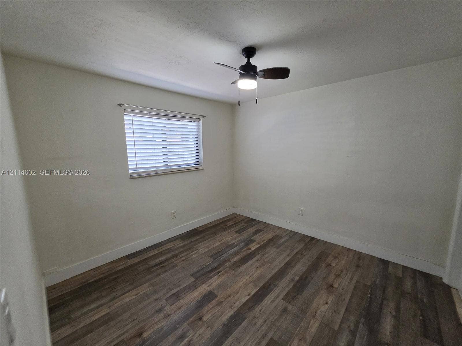 8450 NW 178th Street, Hialeah, Hialeah, FL 33015 Interior room featuring wood-finish flooring, a neutral wall palette, a single window with horizontal blinds, and a ceiling-mounted fan with light fixture