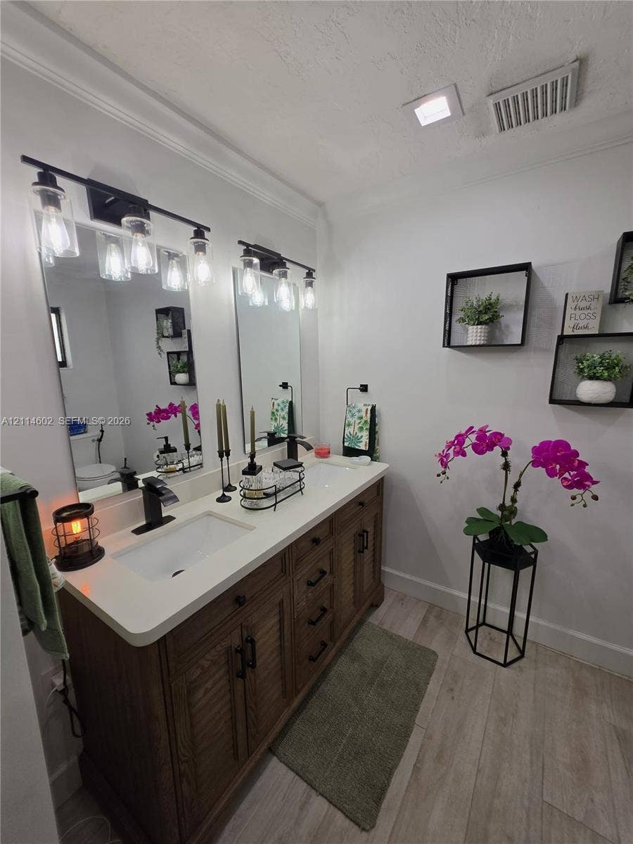8450 NW 178th Street, Hialeah, Hialeah, FL 33015 Double vanity featuring a light-toned countertop, dual rectangular undermount sinks, wood-finish cabinetry, matte black hardware, and two industrial-style light fixtures