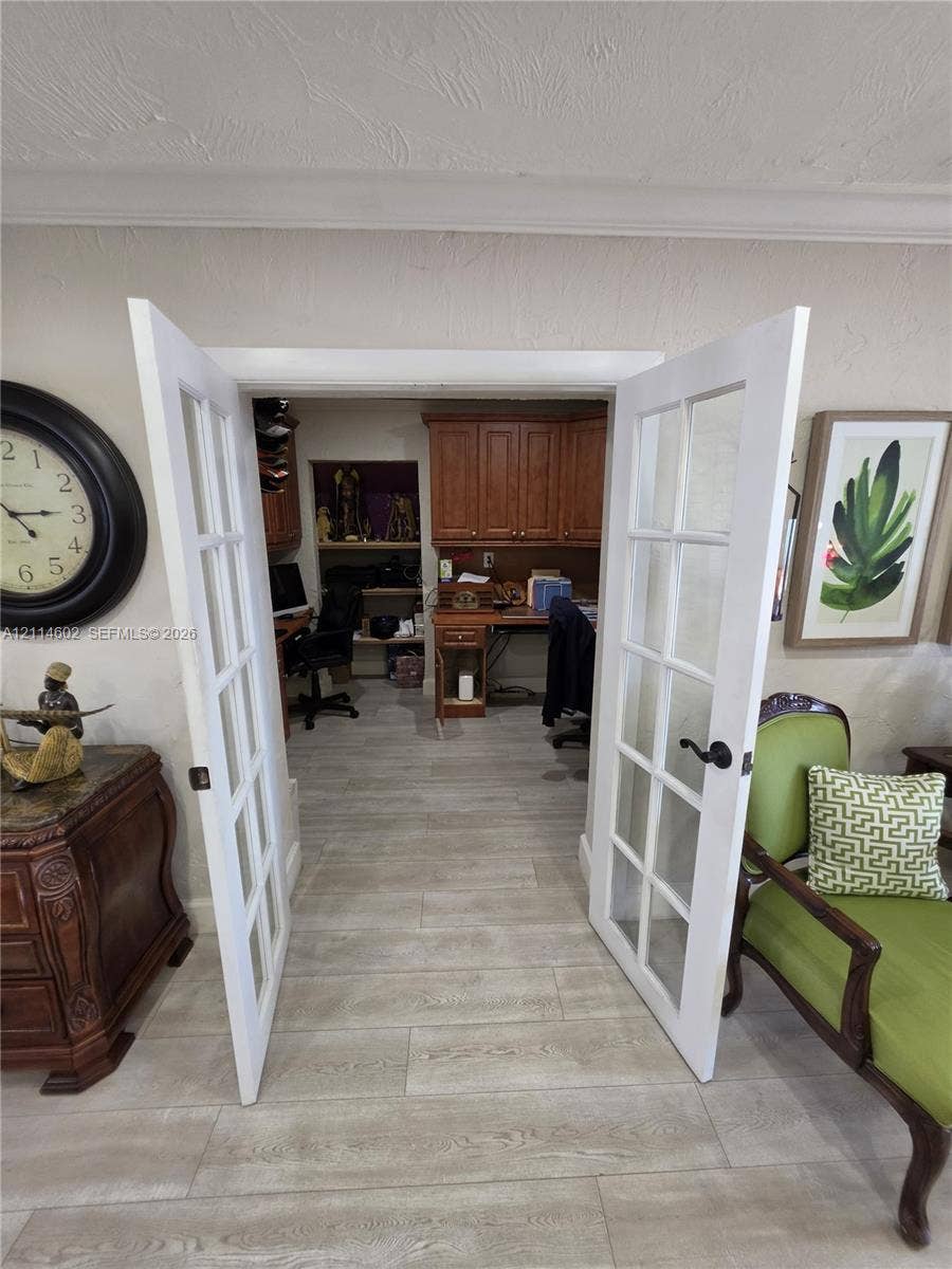8450 NW 178th Street, Hialeah, Hialeah, FL 33015 White French doors featuring multi-pane glass inserts, wood-finish flooring, and built-in wood cabinetry