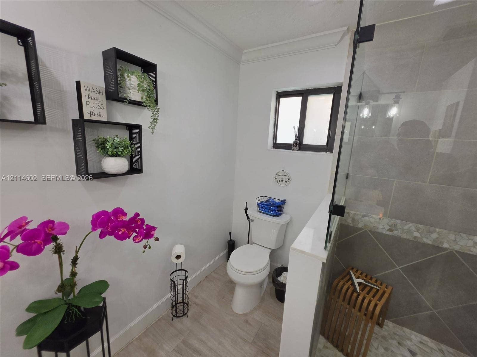 8450 NW 178th Street, Hialeah, Hialeah, FL 33015 Bathroom featuring wood-finish flooring, a glass-enclosed shower with large-format tile walls, mosaic tile accent border, and built-in wall shelving