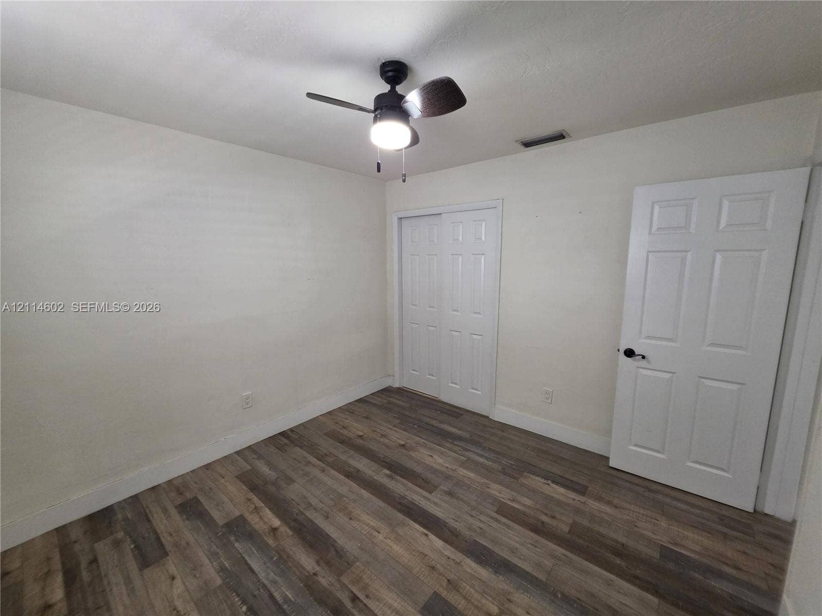 8450 NW 178th Street, Hialeah, Hialeah, FL 33015 Wood-finish flooring, six-panel interior door with matte black hardware, sliding closet doors, and ceiling fan with integrated lighting