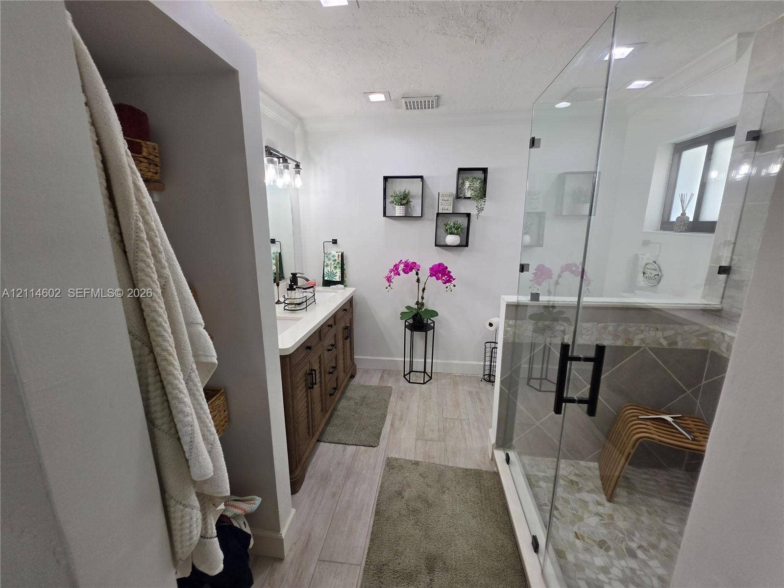 8450 NW 178th Street, Hialeah, Hialeah, FL 33015 Bathroom featuring a wood-finish vanity with a light-toned countertop, walk-in glass-enclosed shower with tile surround, mosaic floor tiling, and wood-finish flooring