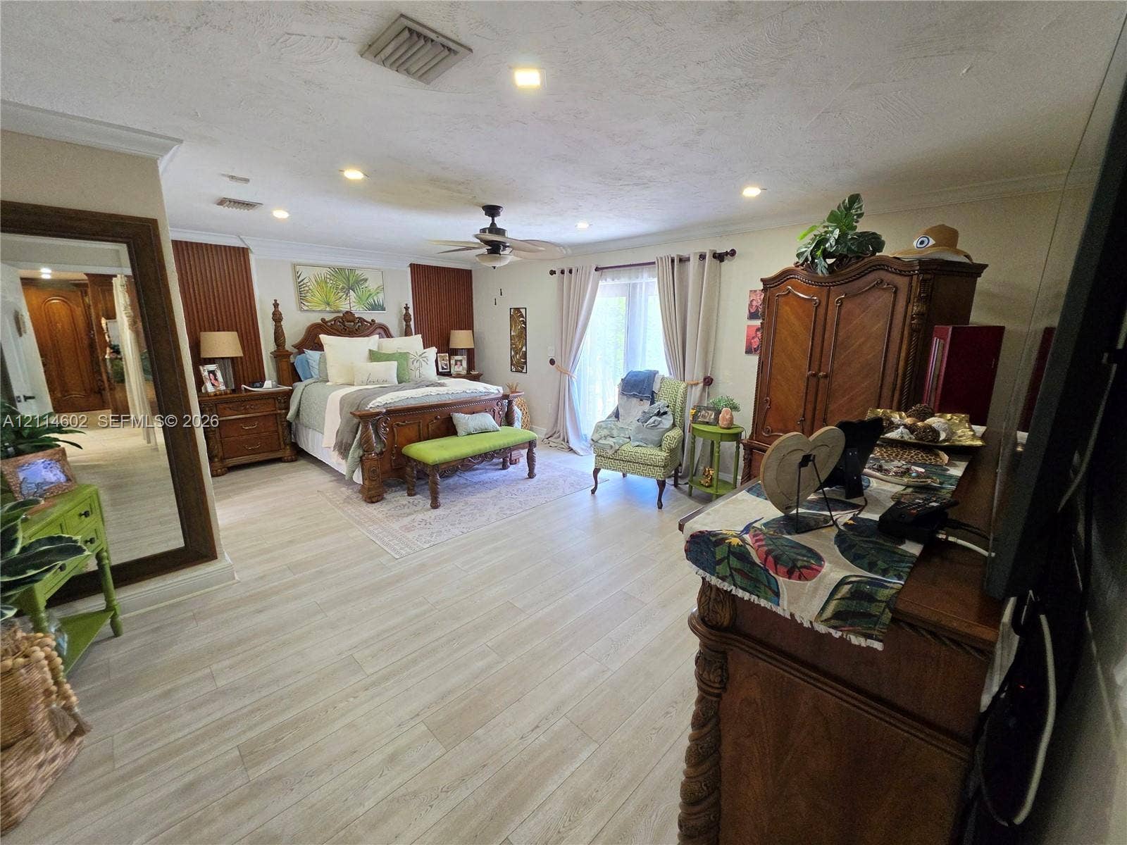 8450 NW 178th Street, Hialeah, Hialeah, FL 33015 Spacious interior featuring wood-finish flooring, recessed lighting, crown molding, vertical wall paneling, and sliding glass doors