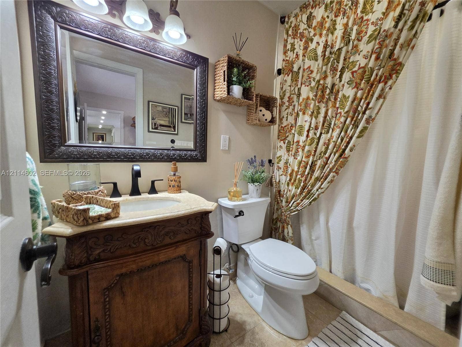8450 NW 178th Street, Hialeah, Hialeah, FL 33015 Carved wooden vanity featuring an integrated basin and countertop, ornate framed wall mirror, and three-light decorative fixture