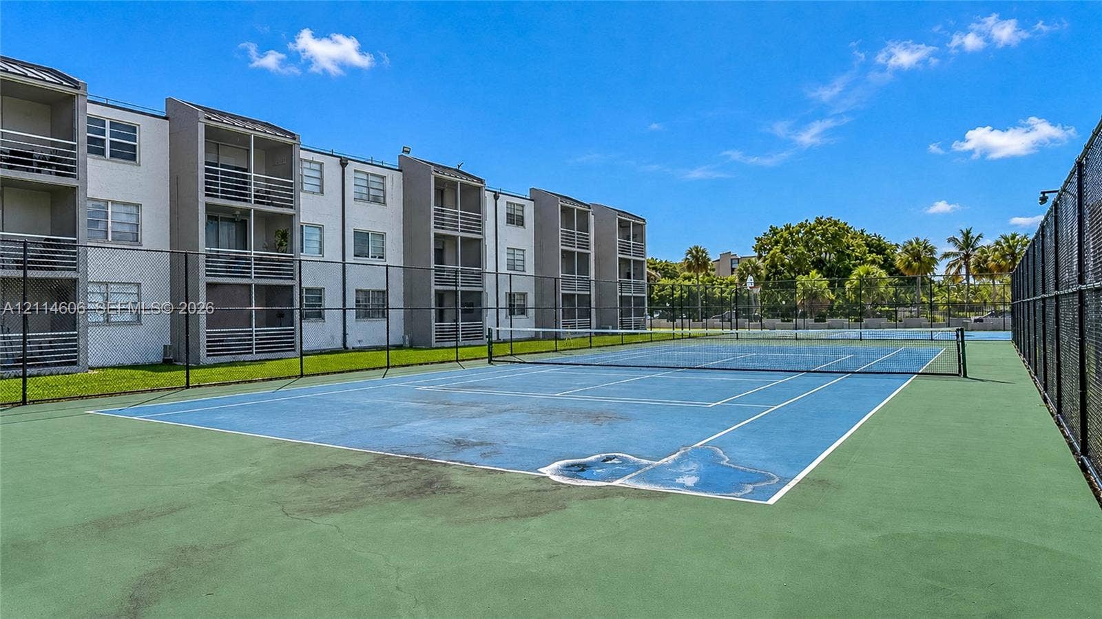 14155 SW 87th Street, #404-E, Miami, FL 33183 Hard-surface tennis court featuring perimeter chain-link fencing and mesh privacy screening