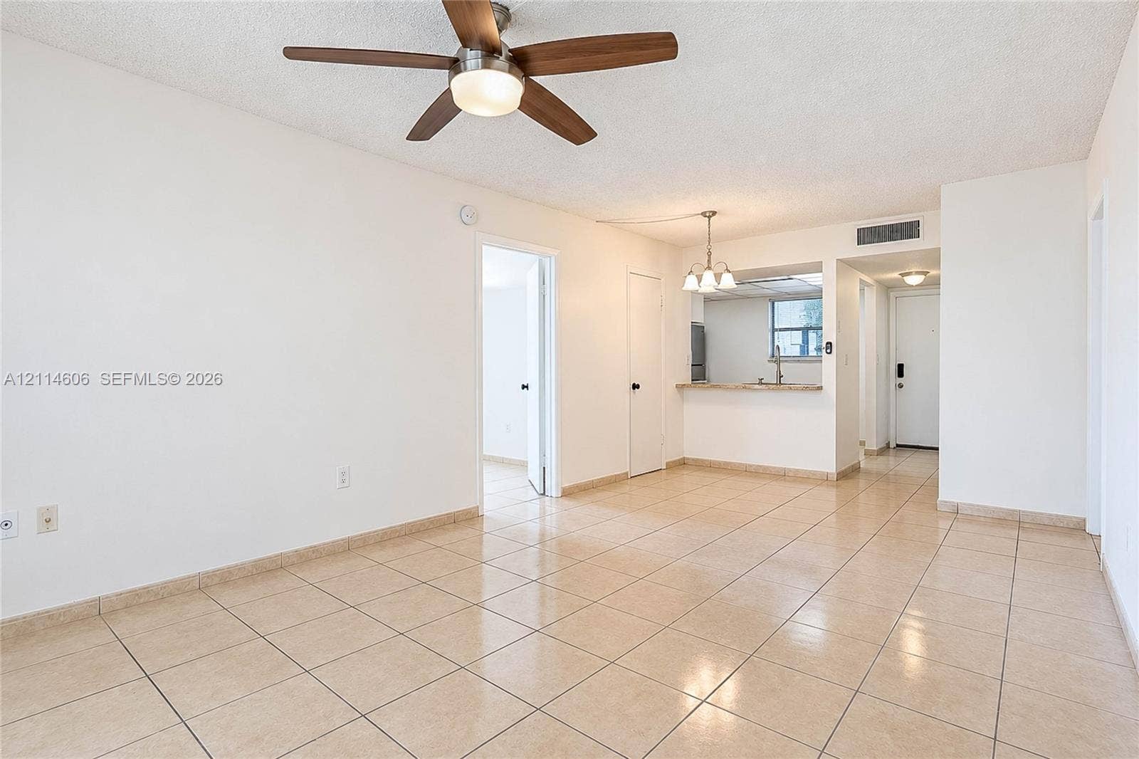 14155 SW 87th Street, #404-E, Miami, FL 33183 Neutral-toned tile flooring, ceiling fan with integrated lighting, built-in breakfast bar, and multi-light chandelier fixture