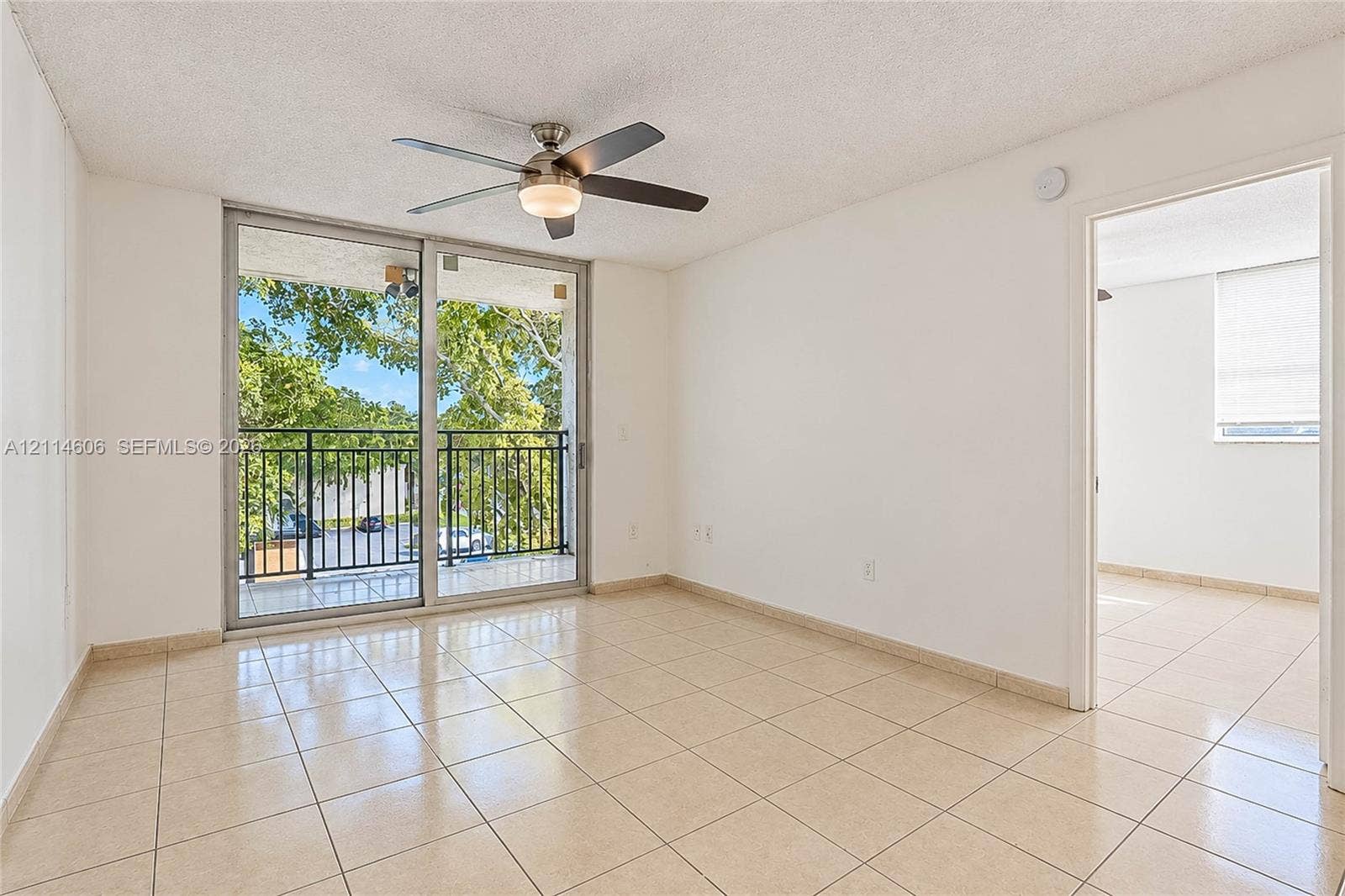 14155 SW 87th Street, #404-E, Miami, FL 33183 Interior featuring neutral ceramic tile flooring, sliding glass doors to a balcony, and a ceiling-mounted fan with integrated light fixture