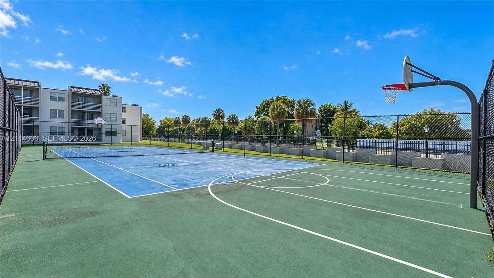 14155 SW 87th Street, #404-E, Miami, FL 33183 Multi-purpose court featuring a basketball hoop, tennis court markings, chain-link perimeter fencing, and concrete surface