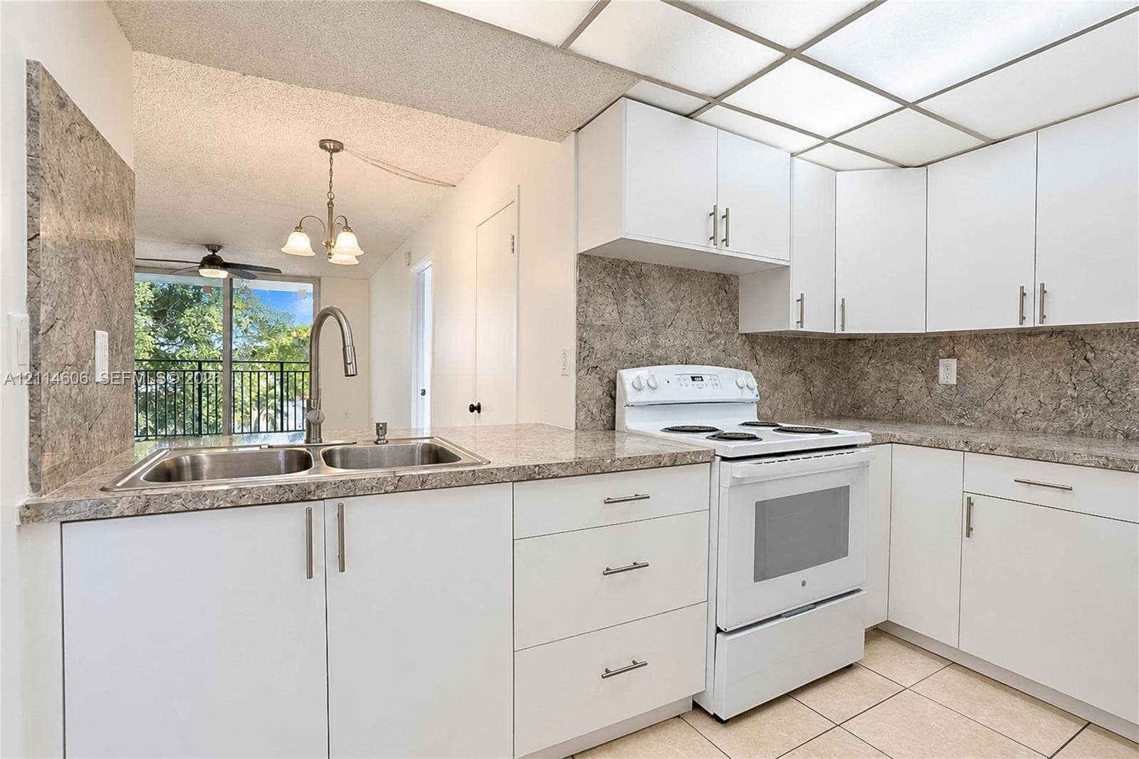14155 SW 87th Street, #404-E, Miami, FL 33183 Kitchen featuring white cabinetry with silver-tone hardware, stone-patterned laminate countertops, matching full-height backsplash, white electric range, and double-basin stainless steel sink with high-arc faucet