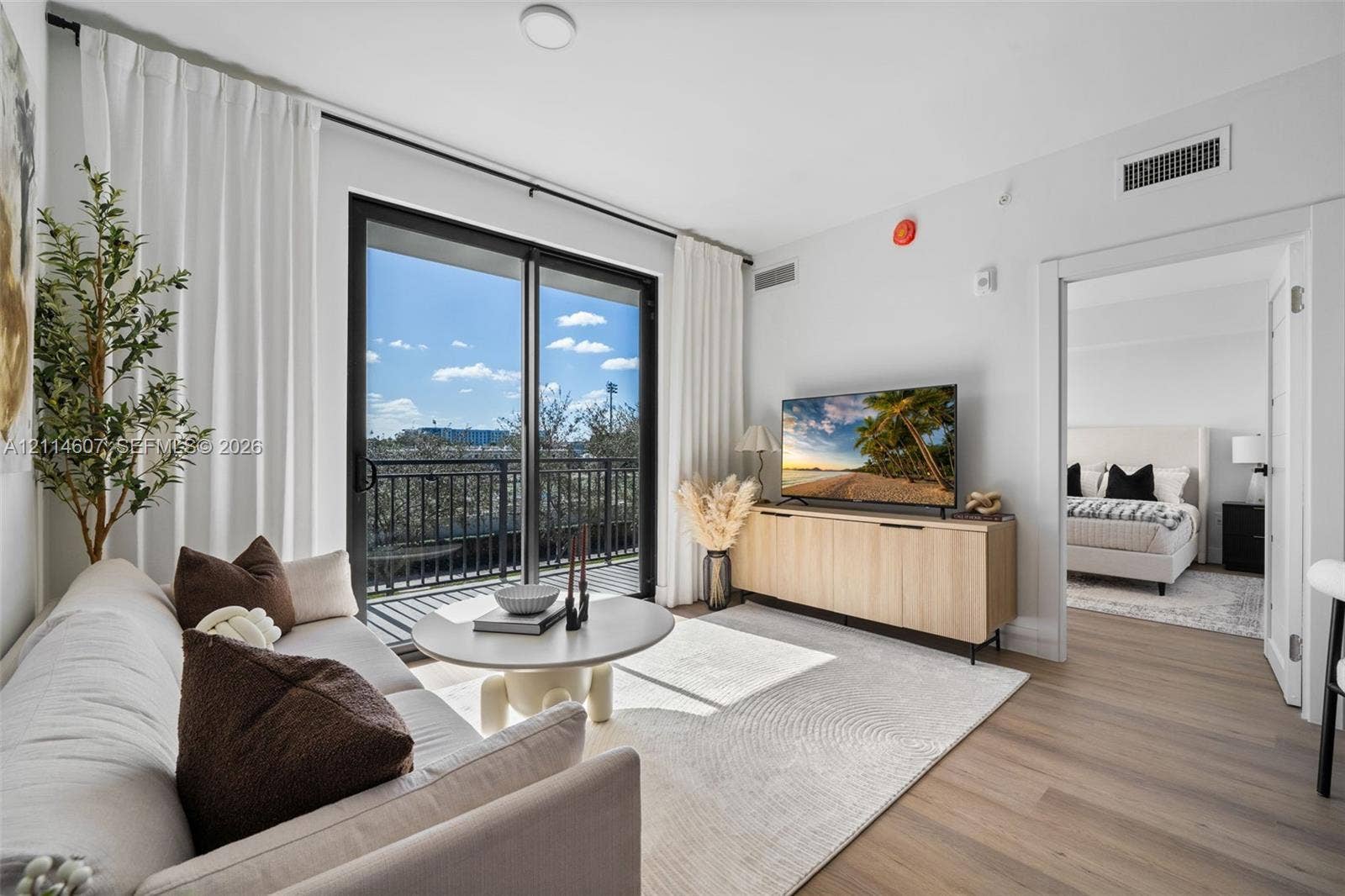 2479 NE 192nd Street, #103, Miami, Miami, FL 33180 Living area featuring wood-finish flooring, sliding glass doors, and a metal balcony railing