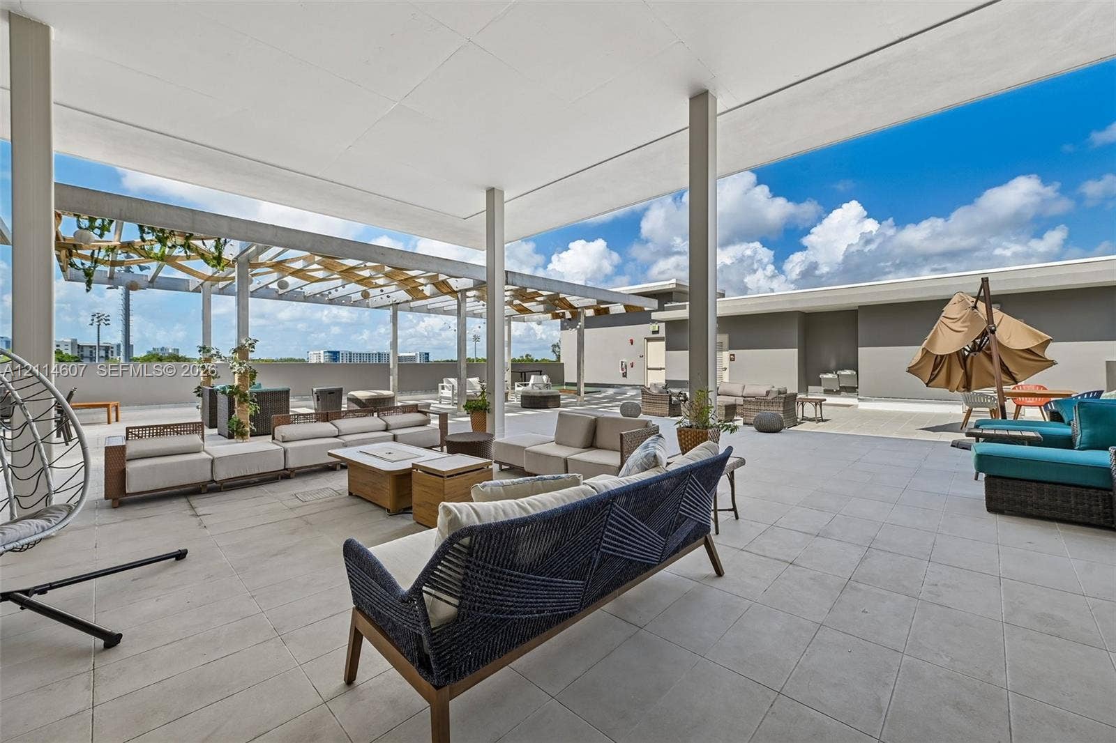 2479 NE 192nd Street, #103, Miami, Miami, FL 33180 Expansive rooftop terrace featuring large-format stone tile flooring, an oversized covered patio area, and an integrated pergola structure
