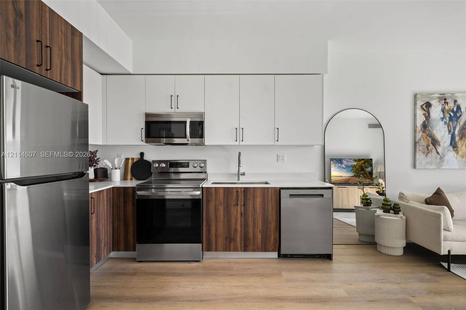2479 NE 192nd Street, #103, Miami, Miami, FL 33180 Kitchen featuring two-tone cabinetry with wood-finish lower and solid-color upper doors, stainless steel appliances, and solid-surface countertops