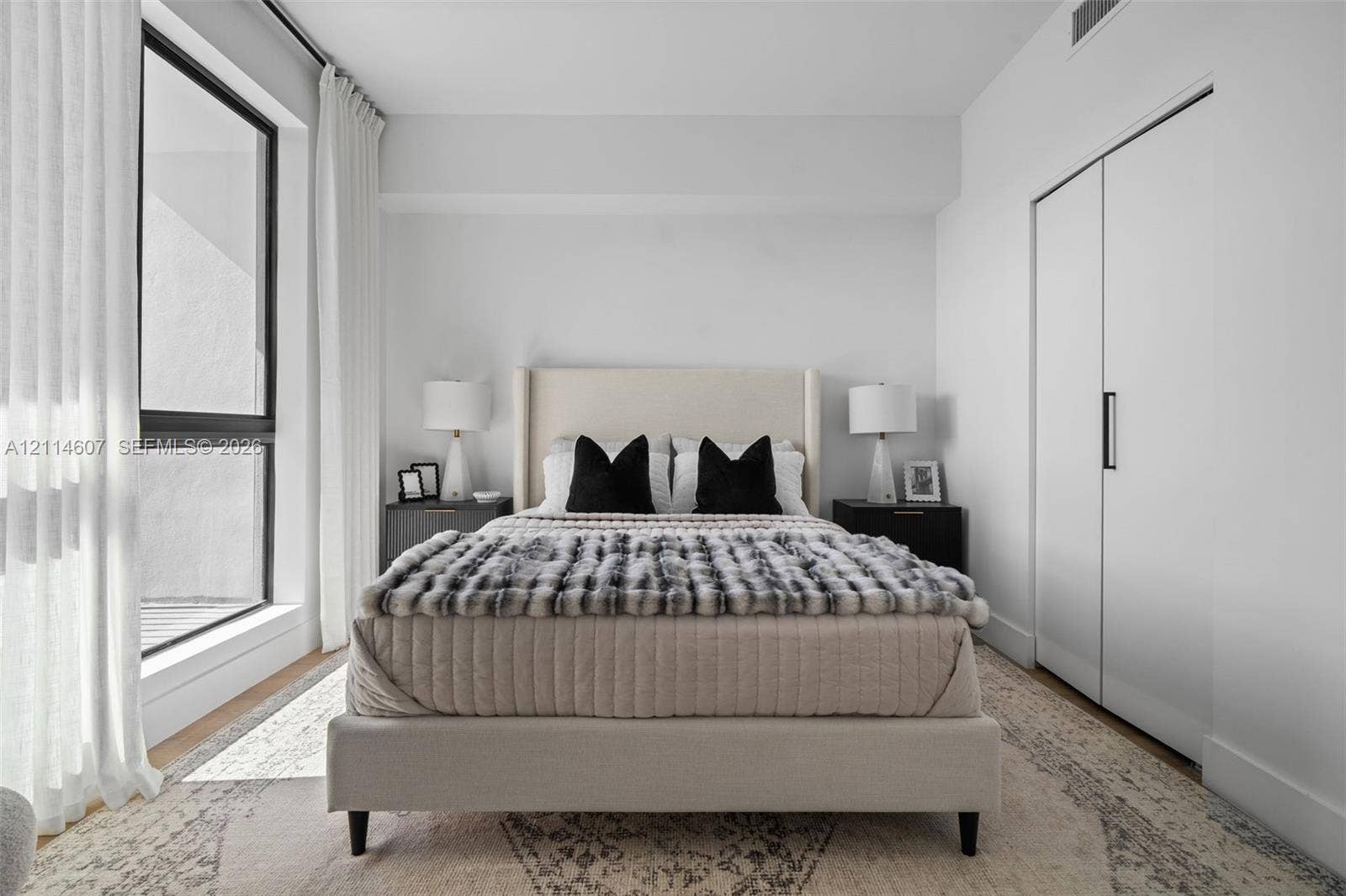 2479 NE 192nd Street, #103, Miami, Miami, FL 33180 Floor-to-ceiling windows with black frames, wood-finish flooring, and built-in closet with matte black hardware