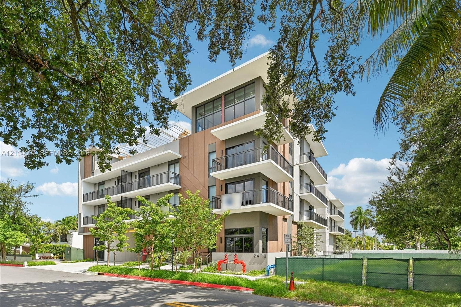 2479 NE 192nd Street, #103, Miami, Miami, FL 33180 Contemporary multi-story exterior featuring vertical wood-finish siding, white structural cantilevered balconies, metal railings, and expansive glass window walls