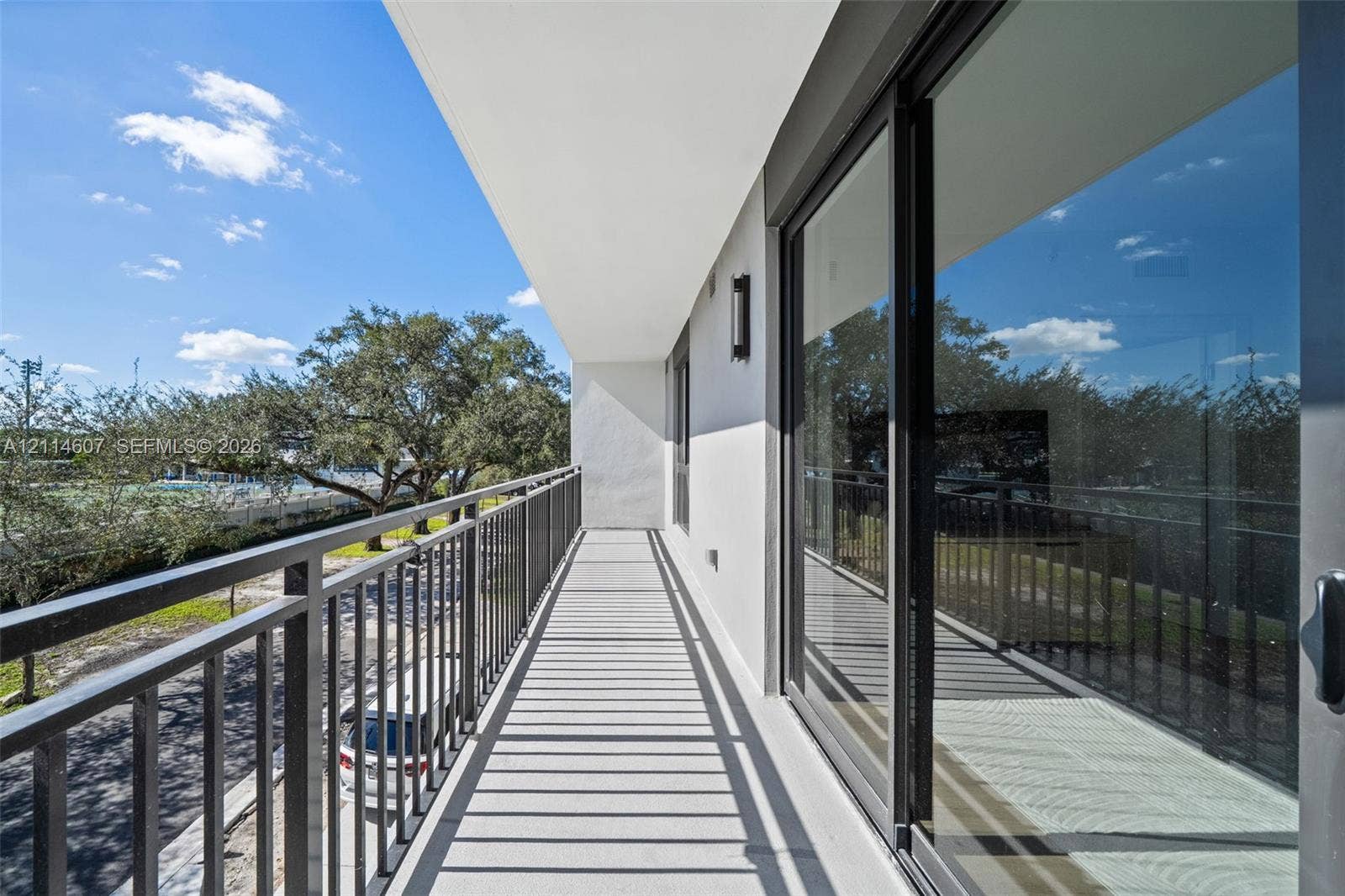 2479 NE 192nd Street, #103, Miami, Miami, FL 33180 Covered balcony featuring metal railings, concrete flooring, and sliding glass door entry