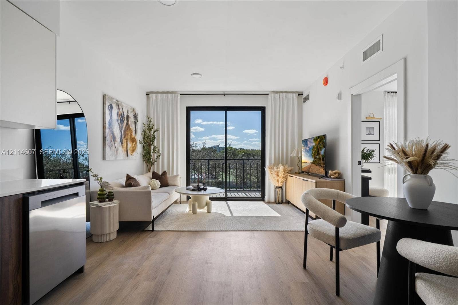 2479 NE 192nd Street, #103, Miami, Miami, FL 33180 Open-concept living space featuring wood-finish flooring, sliding glass doors, and a private balcony