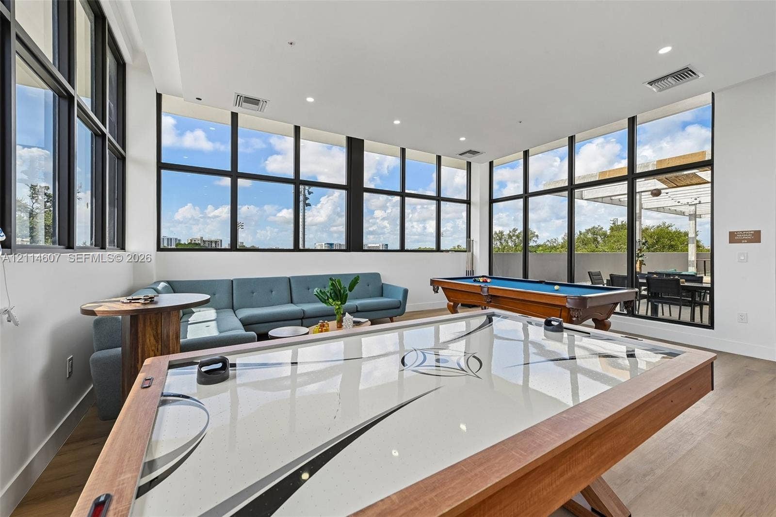 2479 NE 192nd Street, #103, Miami, Miami, FL 33180 Expansive common area featuring floor-to-ceiling black-frame windows, recessed lighting, and light wood-finish flooring