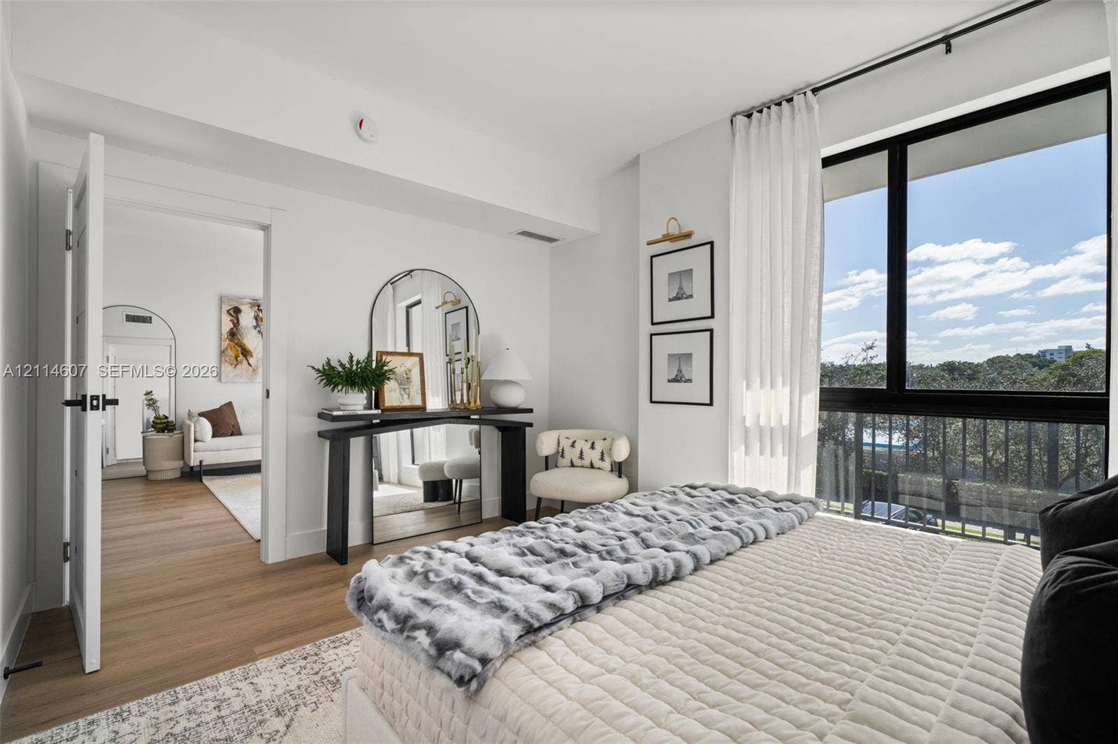 2479 NE 192nd Street, #103, Miami, Miami, FL 33180 Interior space featuring wood-finish flooring, floor-to-ceiling windows with black framing, and a metal balcony railing