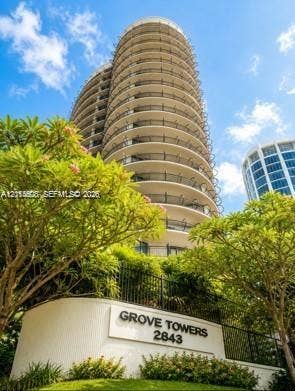 High-rise residential building featuring a curved architectural design, extensive wrap-around balconies, and landscaped grounds