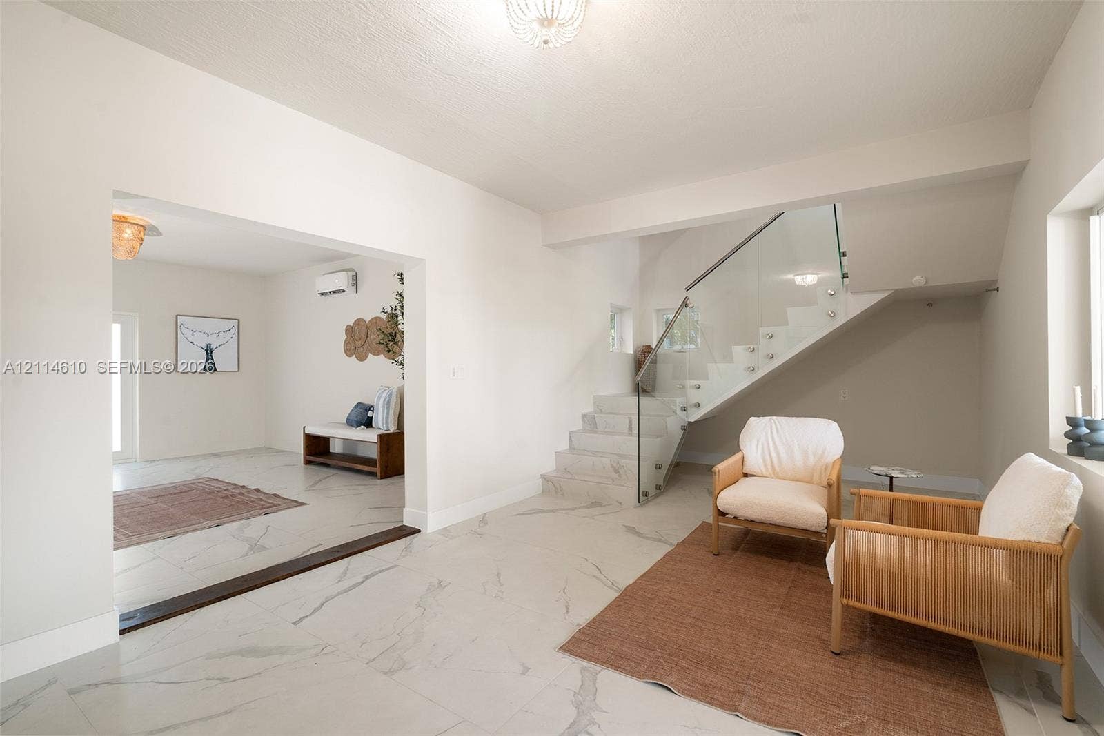 131 Ojibway Avenue, Islamorada, FL 33070 Large-format stone-finish flooring featuring prominent veining, open-riser staircase with glass balustrade, wall-mounted air conditioning unit, and flush-mount decorative ceiling lighting