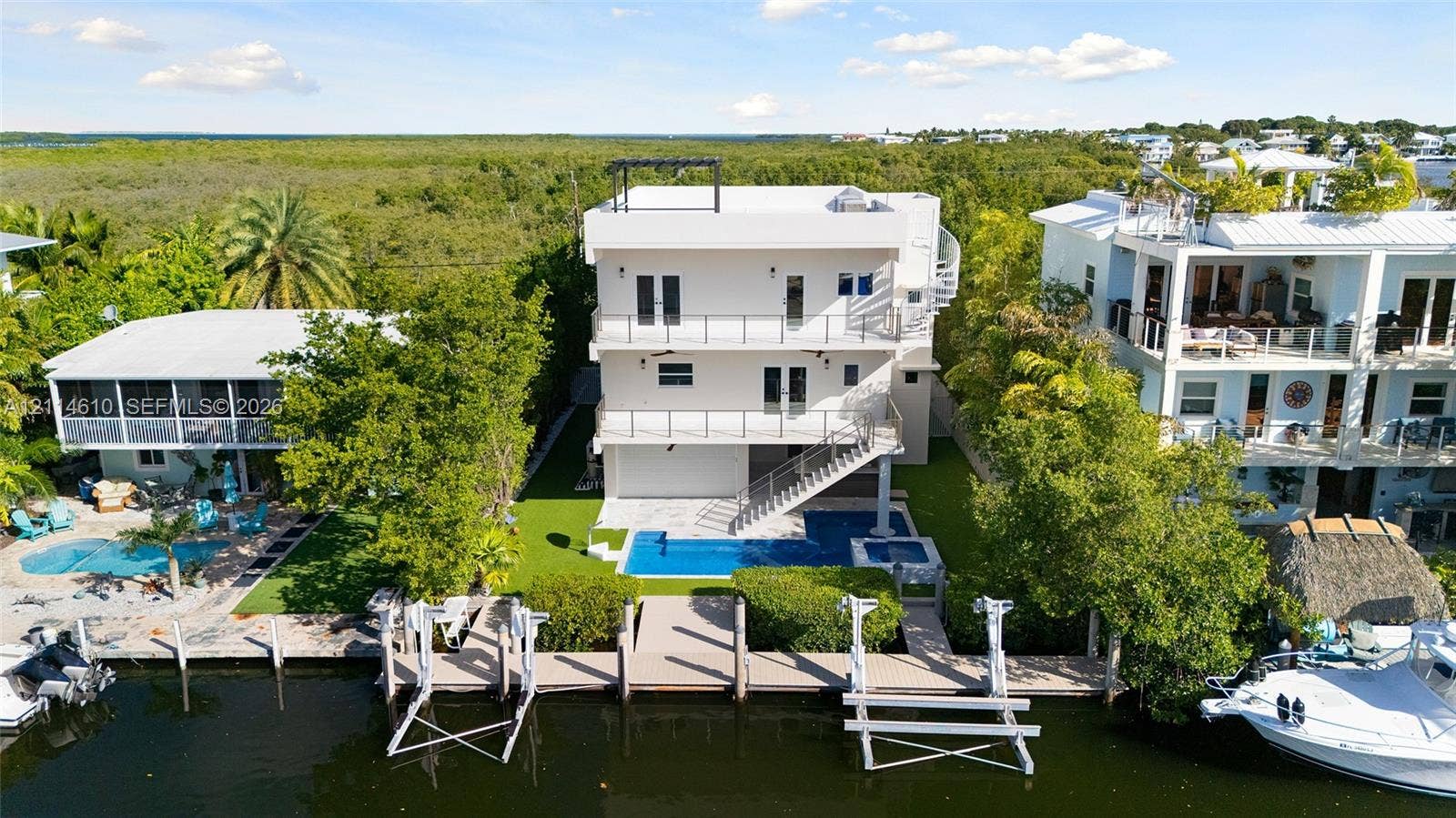 131 Ojibway Avenue, Islamorada, FL 33070 Multi-level coastal residence featuring three stacked balconies, a private swimming pool with integrated spa, and a bulkhead-reinforced canal dock with dual boat lifts