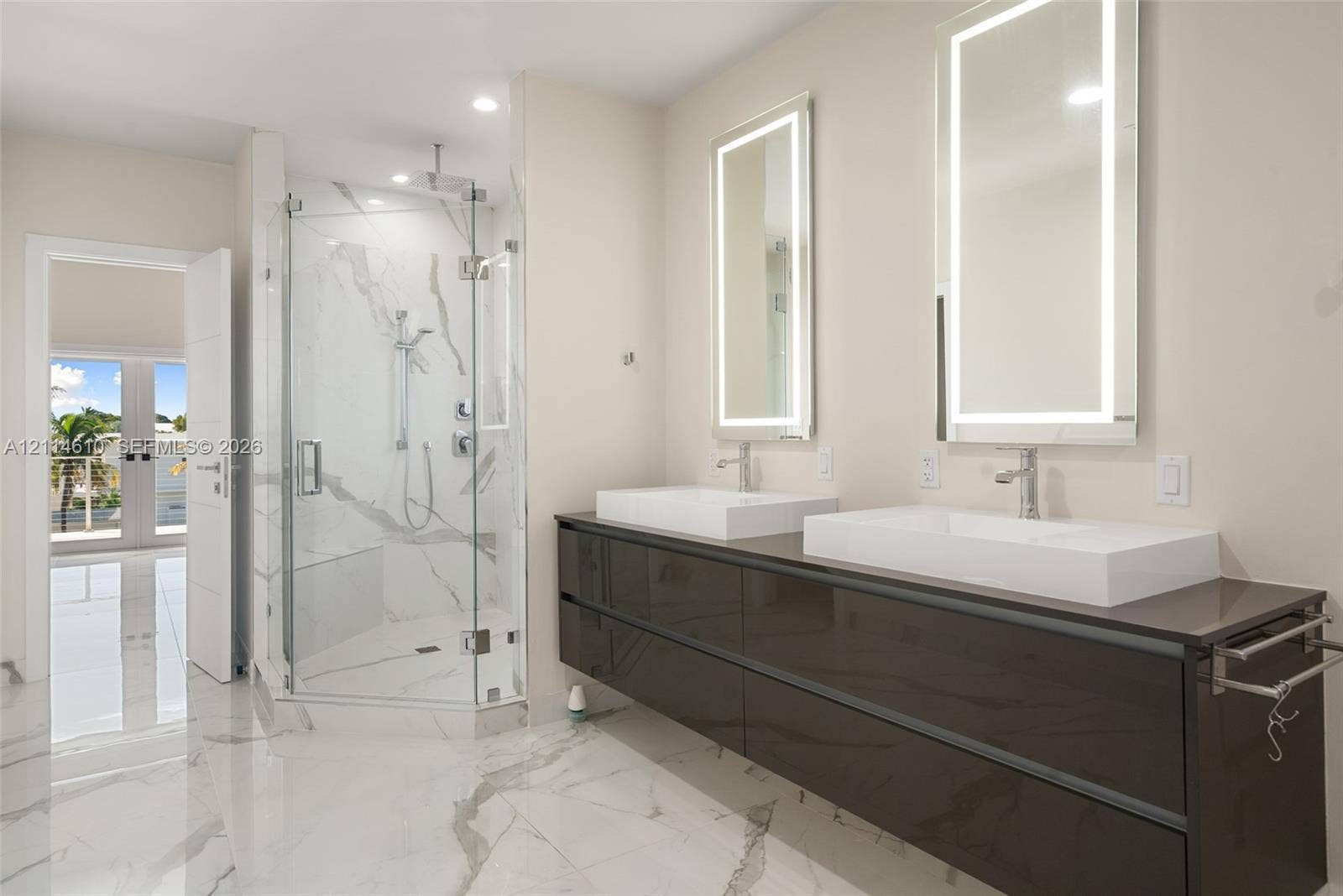 131 Ojibway Avenue, Islamorada, FL 33070 Floating dual vanity with vessel sinks, stone-finish flooring, glass-enclosed walk-in shower with stone-finish wall tile, and backlit vanity mirrors