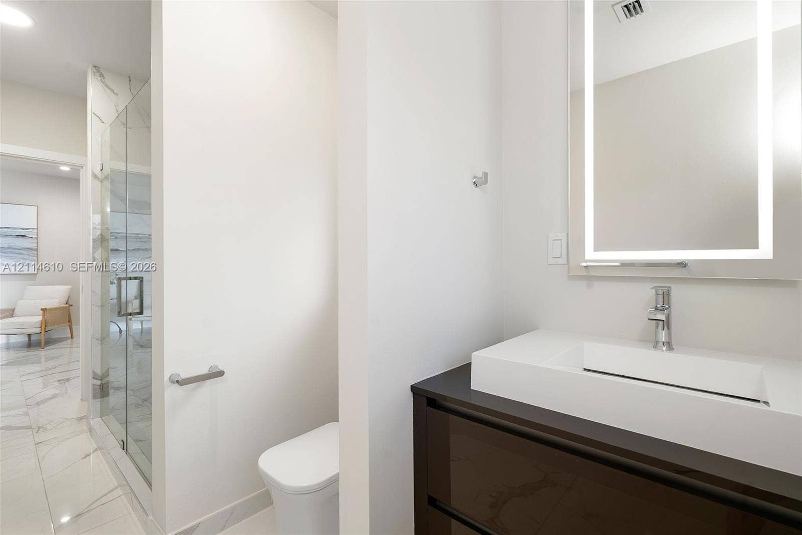 131 Ojibway Avenue, Islamorada, FL 33070 Floating vanity with integrated sink, stone-surface countertop, LED-backlit mirror, glass-enclosed shower with large-format tile surrounds, and tile flooring