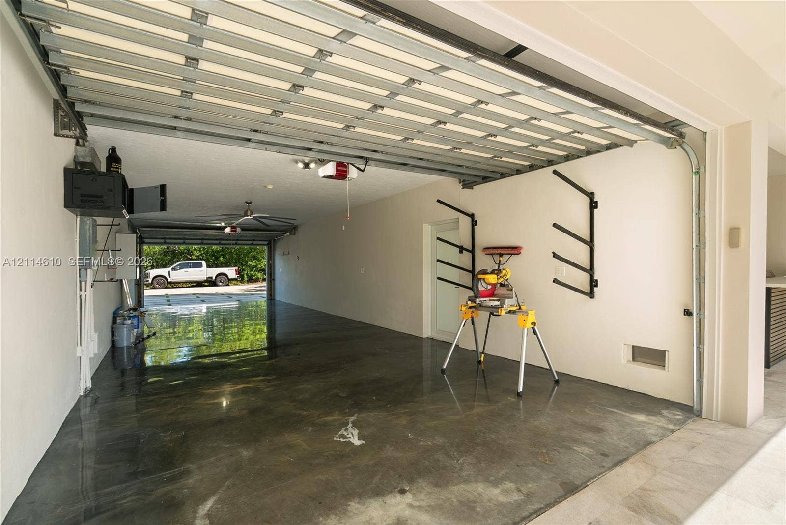 131 Ojibway Avenue, Islamorada, FL 33070 Attached garage featuring epoxy-coated flooring, dual-door access, ceiling-mounted lighting, and wall-mounted storage racks